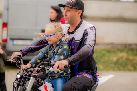 Usměvavé dítě na motorce s jezdcem