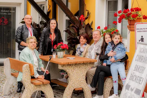 Hosté a rodiny u stolu před vchodem do centra