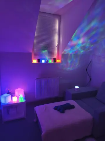 Senzorická místnost v tlumeném fialovém světle s lehátkem a svítícími kostkami