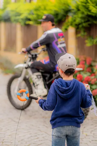 Chlapec s mikrofonem vítá jezdce na motorce